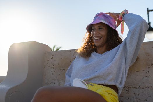 Portrait of an attractive young black woman sitting relaxed outdoors with her mask off. Concept new tourism way