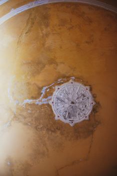 Round decorative clay stucco relief molding with floral ornaments on old ceiling . Haunted house interior concept.