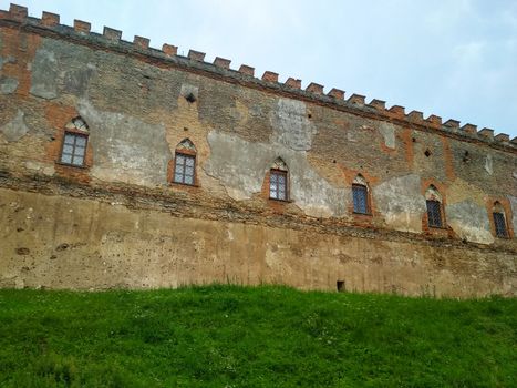 defensive wall of the old castle with an earthen rampart and grass at the foot