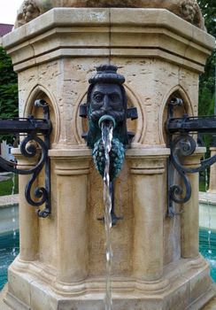 fountain in the park in the form of heads in different directions from the mouth water pours
