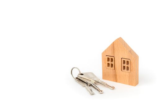Wooden house model with keys on white background for housing and property concept