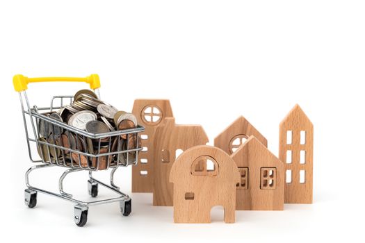 Wooden house model with full of coins in shopping cart on white background for business, finance and property investment concept