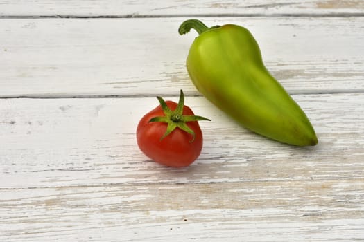 red tomato and green bell pepper pod on a wooden vintage table