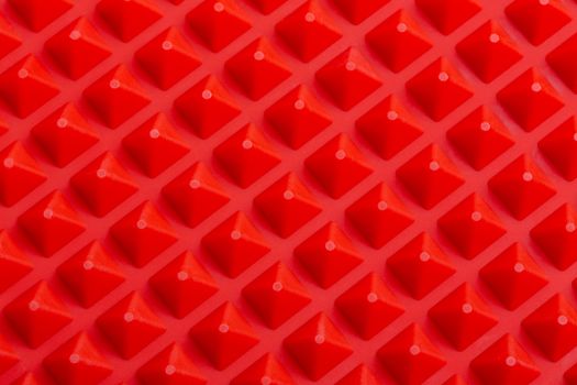 abstract red silicone pyramids array close-up background.
