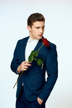 A man in a suit with a rose in his hands a gift date light background. High quality photo