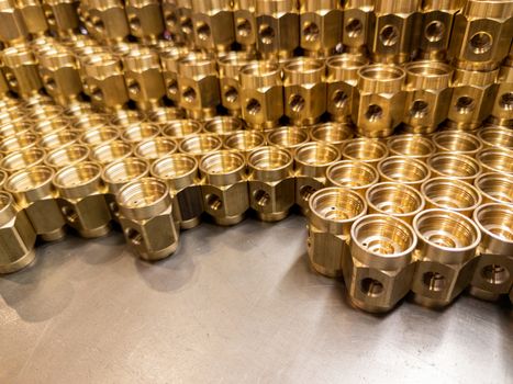 Shiny yellow metal parts background. An abstract industrial close-up background of shiny brass metal threaded hexagonal parts after turning and machining.