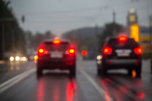 Defocused picture of evening city street car traffic after rain - view from road.
