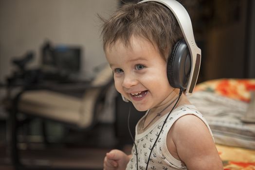 Charming boy listening to music in headphones in a room