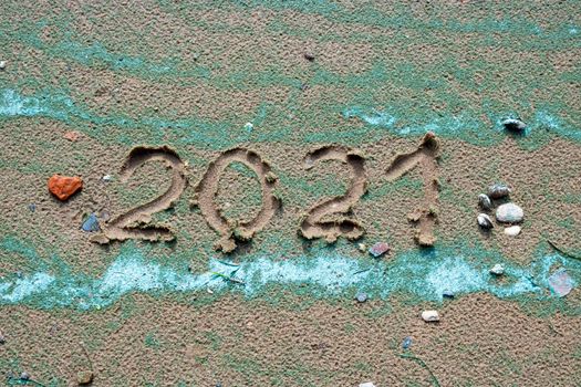 A small red stone - the heart and numbers of 2021 on the sand. Summer beach holidays . The message is handwritten.The concept of a New year.