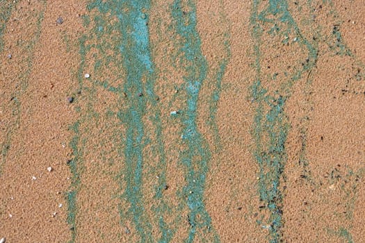 Sandy texture.Background of wet river sand with turquoise stripes of foam.The concept of the environment.