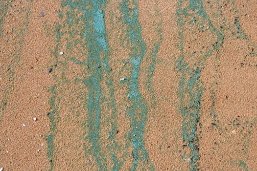 Sandy texture.Background of wet river sand with turquoise stripes of foam.The concept of the environment.