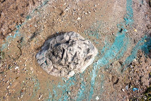 The stone lies in the sand on the coast.Nearby is a turquoise strip of river foam from the fuel.The concept of the environment.