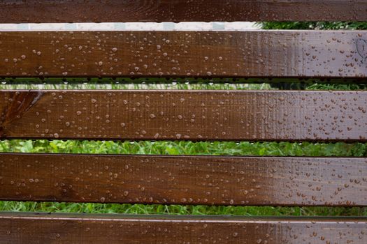 Drops of water on wooden bench after the rain, natural weather background.