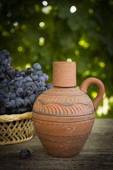 Clay jug with wine and grapes outdoors