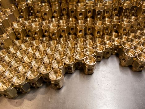 Shiny yellow metal parts background. An abstract industrial close-up background of shiny brass metal threaded hexagonal parts after turning and machining.
