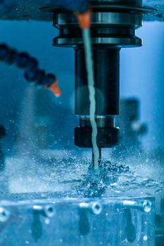 A close-up view on collet chuck and swarf wrapped over carbide drill while cnc drilling under liquid coolant. Feed and cutting speed adjusting problem. Milling machine debugging issue.