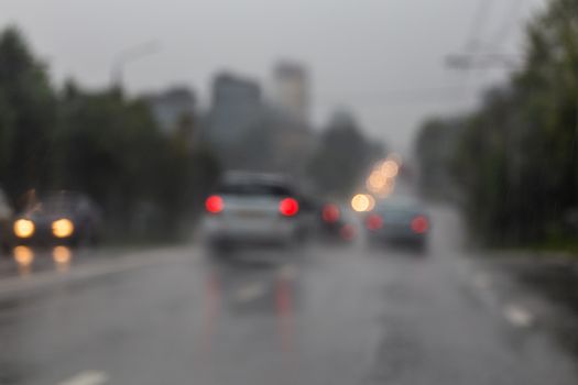 Defocused picture of evening city street car traffic after rain - view from road.