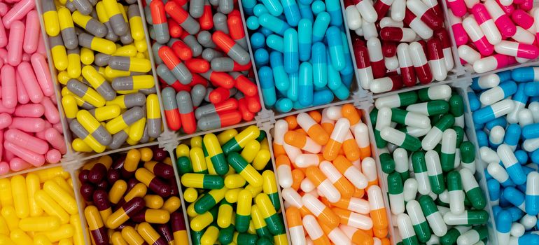 Colorful capsule pills in plastic box. Pharmaceutical industry. Pink, yellow, blue, green, orange, gray, red, and white capsule pills. Healthcare and medicine. Vitamins and supplements concept.