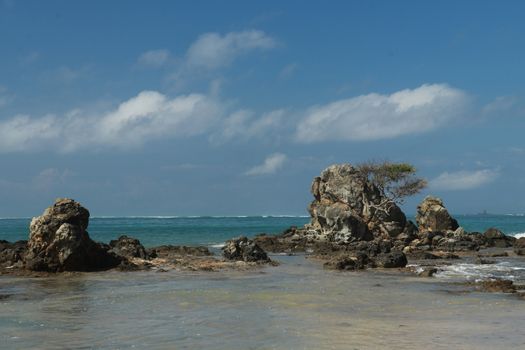 An idyllic beach in Lombok, Indonesia. The Mandalika beach is stony, with many rock formations emerging from the water. Rock formations on beach Kuta beach. Perfect day for relaxation.