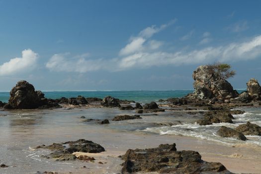 An idyllic beach in Lombok, Indonesia. The Mandalika beach is stony, with many rock formations emerging from the water. Rock formations on beach Kuta beach. Perfect day for relaxation.