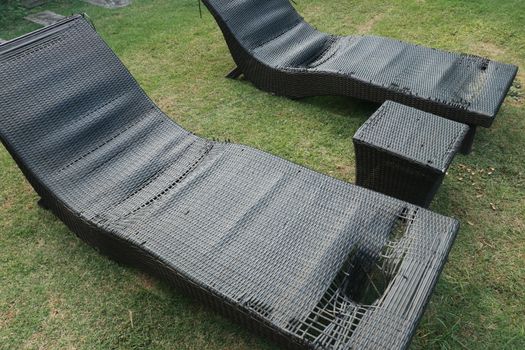 black wicker sun bed isolate with clipping path. old sunbeds in the garden. Torn pool bed on the terrace. Destroyed chair pool by the pool.