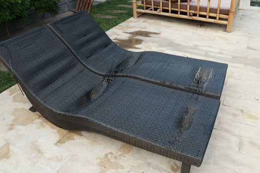 black wicker sun bed isolate with clipping path. old sunbeds in the garden. Torn pool bed on the terrace. Destroyed chair pool by the pool.