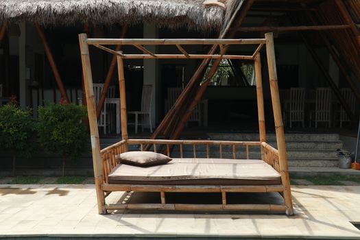 Bamboo bed on the beach. Bamboo deck chair on a paved terrace near the hotel restaurant.