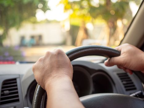 A man's hand held the steering wheel of a car to steer while the car was moving away. Concept and direction of business operations according to the plan.