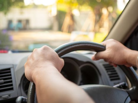 A man's hand held the steering wheel of a car to steer while the car was moving away. Concept and direction of business operations according to the plan. Direction control concept.