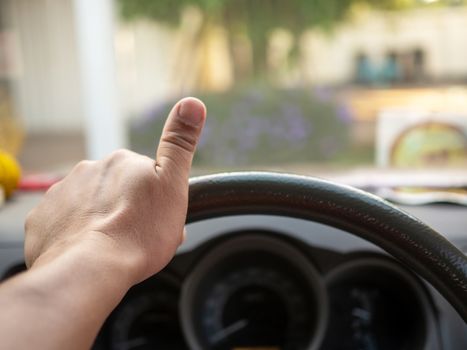 A man's hand holding a car steering wheel To steer the car while driving. Concept of business direction Following the plan.