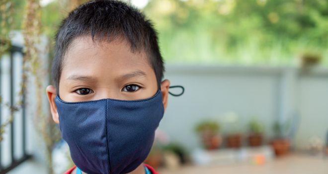 Close-up portrait of a cute boy wearing a protective mask and he is looking at the camera.