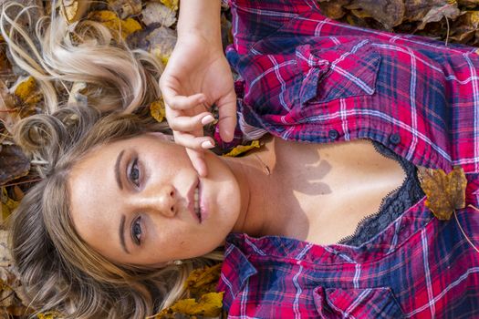A gorgeous blonde model enjoys a Autumn day outdoors in a park