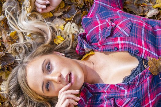 A gorgeous blonde model enjoys a Autumn day outdoors in a park