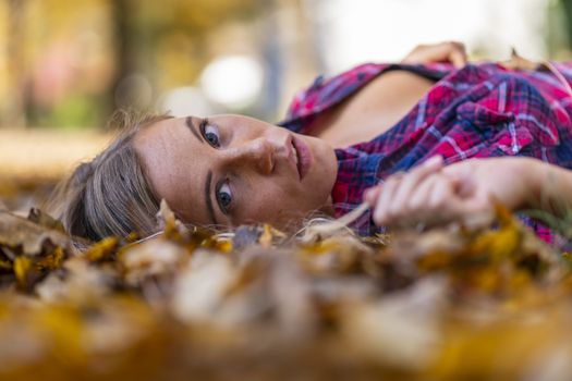 A gorgeous blonde model enjoys a Autumn day outdoors in a park