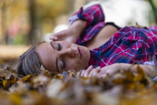 A gorgeous blonde model enjoys a Autumn day outdoors in a park