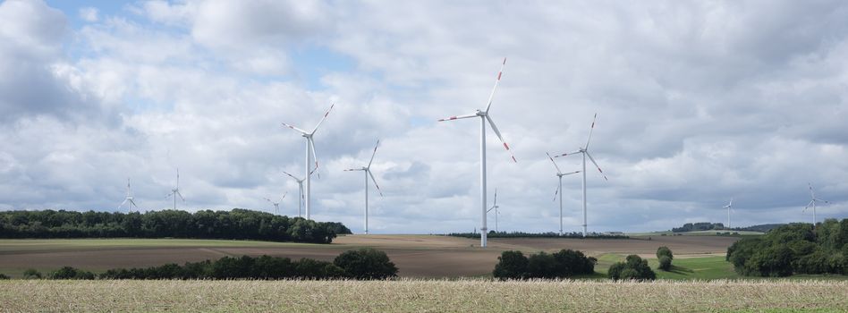 fields and wiind turbines in german eifel under cloudy sky in summer