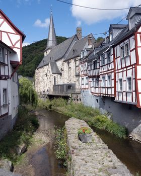 river and half timbered houses near church in beautiful village of Monreal in german eifel