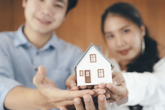 Young couple showing house model. Real estate, buy or sale or moving home or renting property. Mortgage and business concept.