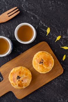 Moon cake yolk pastry, mooncake for Mid-Autumn Festival holiday, top view design concept on dark wooden table with copy space, flat lay, overhead shot