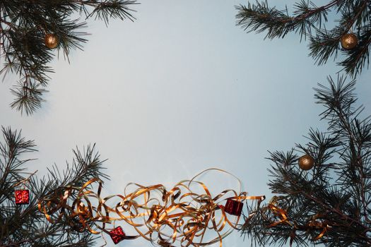 coniferous branches and Christmas tree decorations on a New Year's blue background, copy space.