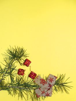 coniferous branches and Christmas tree decorations on a New Year's yellow background, copy space.