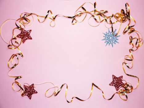 wavy frame made of gold ribbon with stars and snowflake on pink background, copy space for new year, christmas.