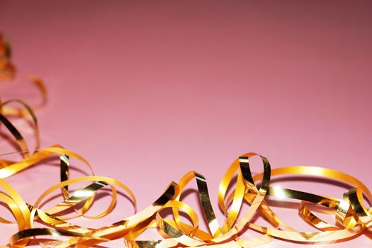 wavy gold ribbon on pink background, copy space for new year, christmas.