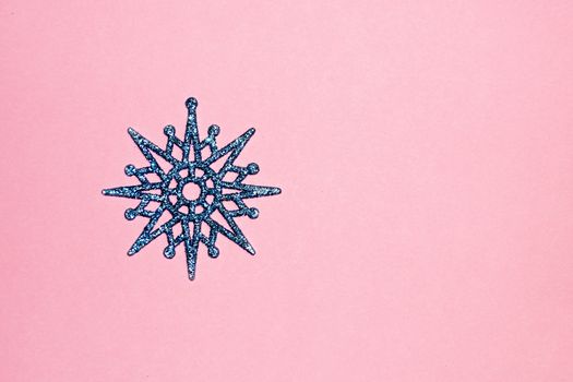 blue snowflake on pink background, copy space for christmas background.