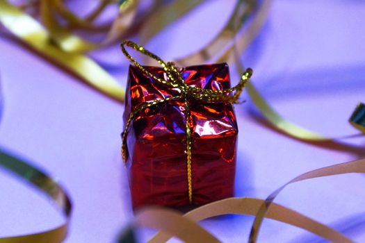 shiny red gift box and gold ribbon on pink background close up