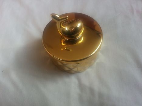 The decorative little golden pot with dolphin lid open, for room decoration. Golden pot on the vintage white background.