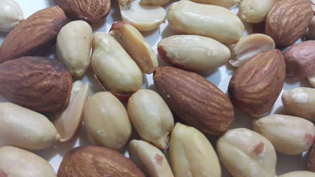 Closeup view of mixed dried and roasted  peanuts and almonds. A fruit for background text