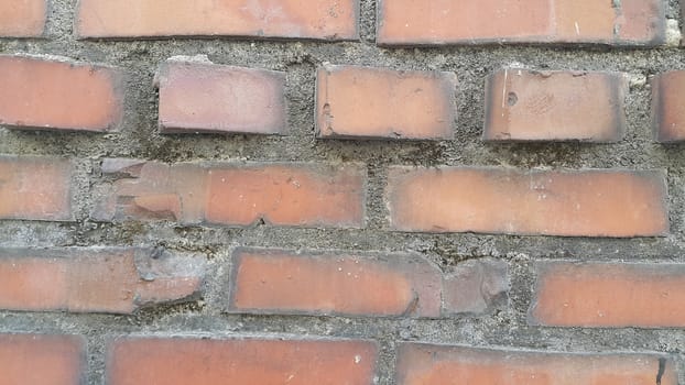 Closeup texture of red brick wall. A background of a weathered old exterior brick wall in the sunshine.