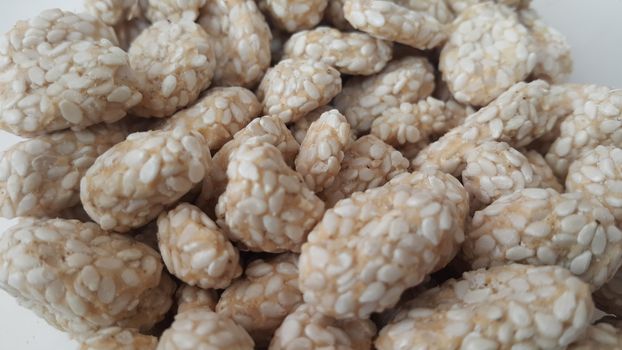 Closeup view of home made Asian sweet food called rewri or rewdi oe sesame seed sweet mad with jaggey and served in a white plate. 