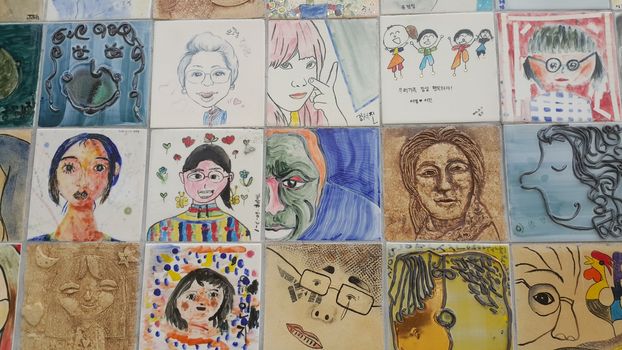 Chuncheon city hall, South Korea-March-25, 2019: Paintings and sculpted faces of people on the concrete wall for memoir in a public park.